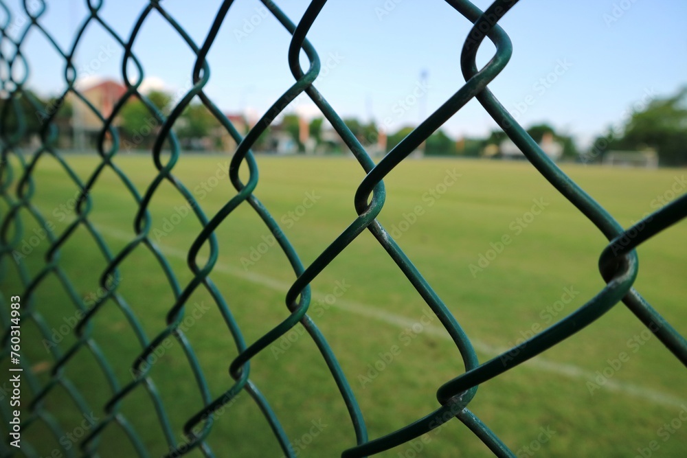 Green soccer field inside the green fence with morning sunlight.