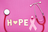 Ribbon and inscription Hope and stethoscope on pink background