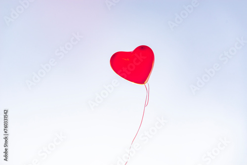 Red heart balloons over blue sky. Love, valentines day, romantic, wadding or birthday background. a red balloon in the shape of a heart is flying away into the blue sky. Letting go of my heart