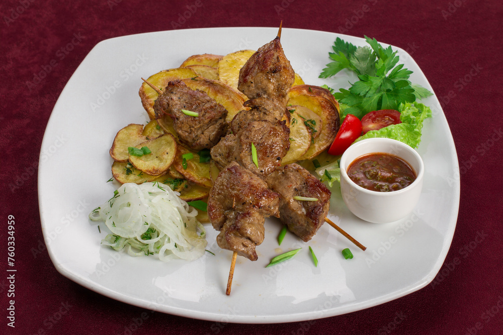 Delicious kebab with fried potatoes on a plate, menu for a restaurant Delicious kebab with fried potatoes on a plate, menu for a restaurant