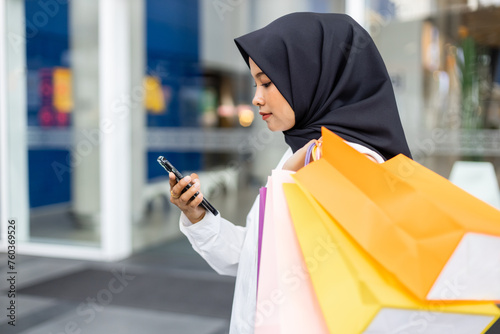 Muslim women wear hijab holding smartphone shopping bag color in supermarket. Female islamic arabic relaxation shopping. fashion lifestyle.