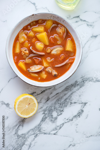 Bowl of manhattan clam chowder on a white marble background, vertical shot with space, top view