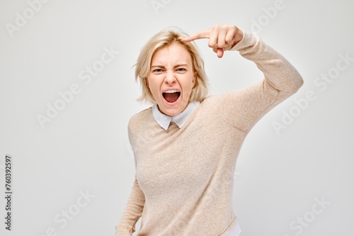 Portrait of angry blond woman points her finger at the camera and yells on white background