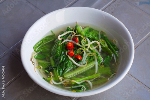 Home made food green mustard vegetables or tumis sayur sawi served in white bowl on the table