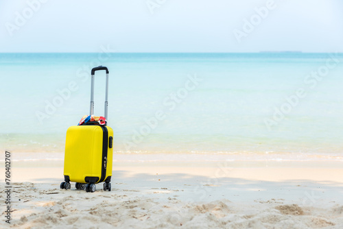 Summer travel and planing with yellow suitcase luggage in the sand beach. Travel in the holiday trips, airplane and blue sky background. Summer and Travel Concept