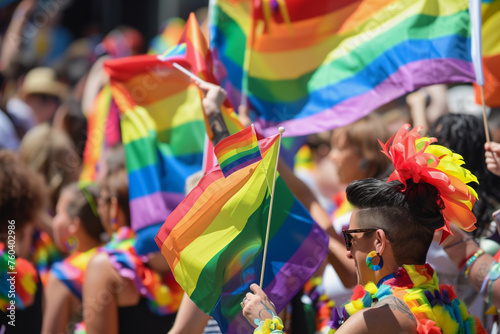 A group of people are holding rainbow flags and smiling. Scene is joyful and celebratory