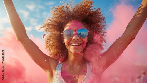 Happy young woman with curly hair and sunglasses having fun at holi festival