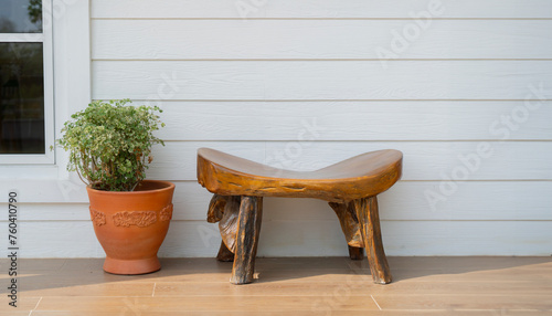 Real wooden chair with clay flower pot at white house balcony on sunny day. © Kunlathida