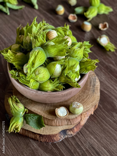 Green hazelnuts in a wooden plate on a brown background. 
 Freshly picked hazelnuts on wooden saws. 