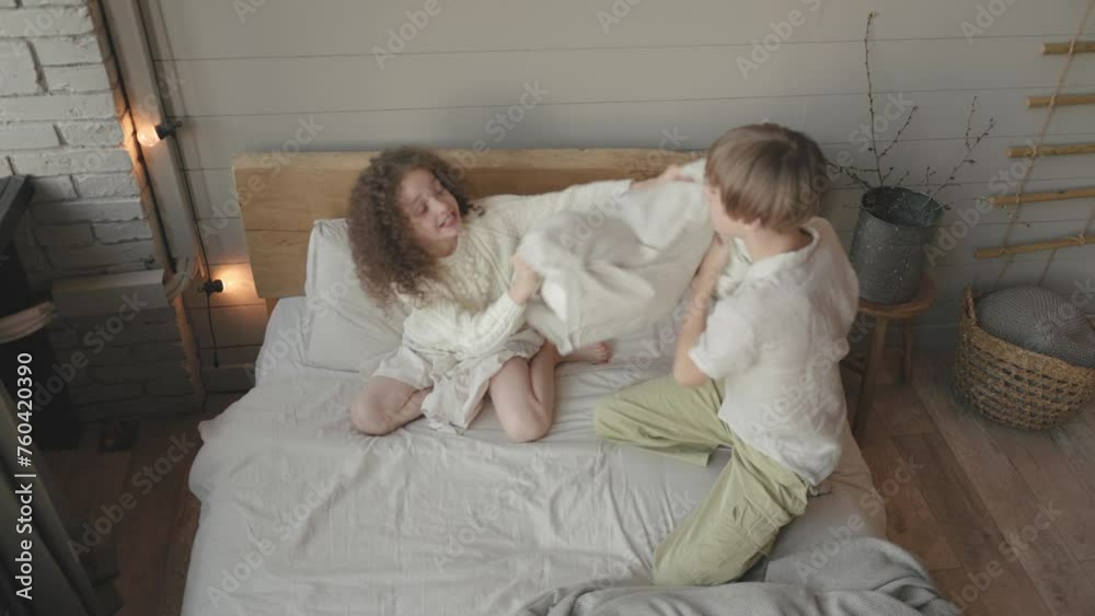 Happy children boy and girl pillow fight on a bed for fun, playing and bonding together. House, funny and kids, family or friends with a game in the bedroom for crazy, laughing and siblings together. Happy children boy and girl pillow fight on a bed for fun, playing and bonding together. House, funny and kids, family or friends with a game in the bedroom for crazy, laughing and siblings together.