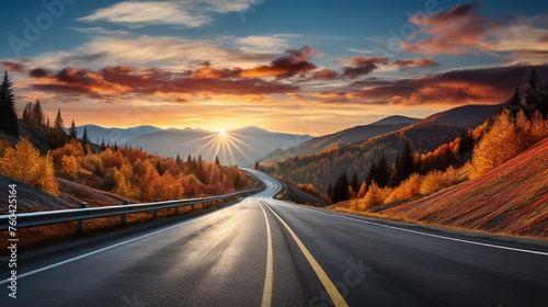 A stunning sunset over a picturesque black asphalt road amidst beautiful scenery 