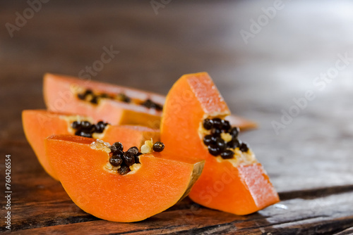 ripe papaya fruit slice with black seed on wooden photo