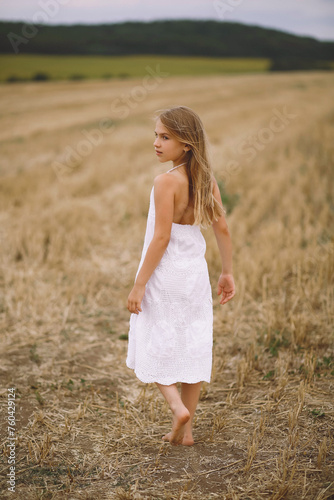 Portrait of a pretty little girl in white summer dress walking