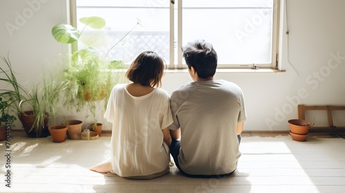 Young couple sitting on the floor at home and looking out the window.Generated by AI