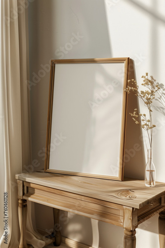A close-up photo of an empty light wooden A4 frame mockup on a table leaning against a wall in a bright room with sunlight coming through a window. A vase with wild flowers sits on the table.