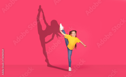 A joyful young girl in a yellow shirt and jeans performs a high leg kick with enthusiasm