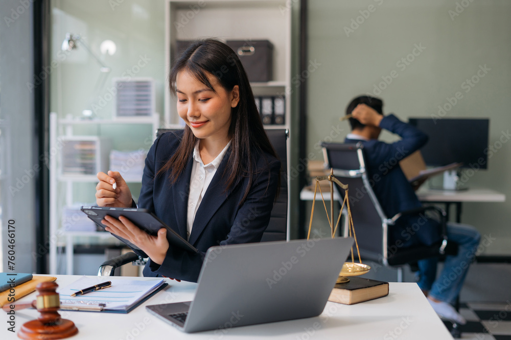 Female Legal counsel working with paperwork on his desk in office workplace working with tablet computer. Justice and law concept. Female Legal counsel working with paperwork on his desk in office workplace working with tablet computer. Justice and law concept.