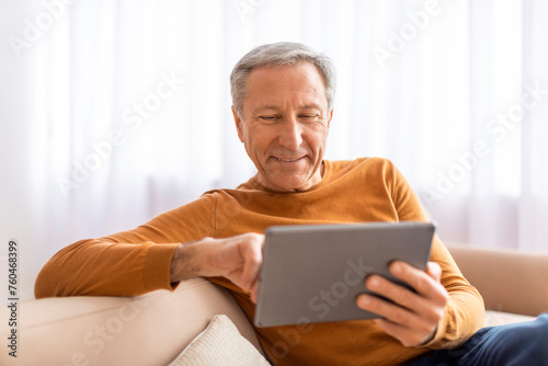 Relaxed senior man using digital tablet at home