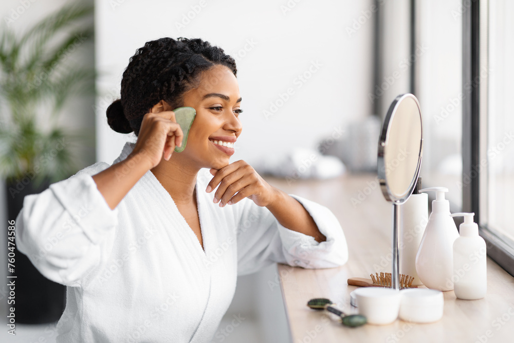 Smiling black woman making skincare routine with jade gua sha scraper Smiling black woman making skincare routine with jade gua sha scraper