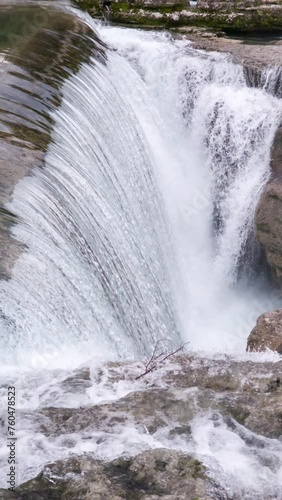 Waterfall on mountain river surrounded by rock. Water falling in big cascade, flowing over a vertical drop cut deep into stone. Natural freshwater resource.