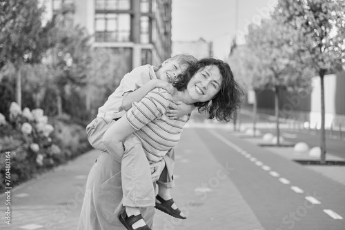 young mother and son smiling looking at the camera in modern residential complex. Having fun together, happy parenting, new home concept. Bright summer day in the urban background. High quality photo