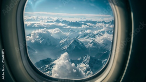 View from an airplane, a picturesque landscape of mountains rising above the clouds opens from the window © AlfaSmart