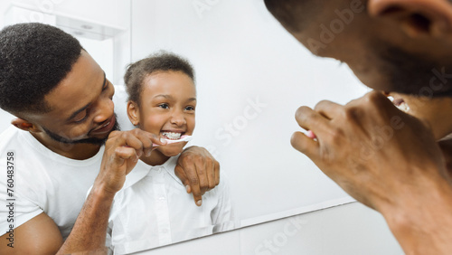 Caring father brushing daughter's teeth in the bathroom photo