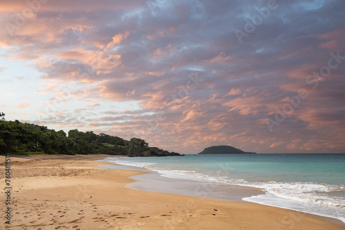 Fototapeta Naklejka Na Ścianę i Meble -  Deserted wide sandy beach with turquoise blue sea. Tropical plants of a bay at sunset in the Caribbean. Plage de Cluny, Basse Terre, Guadeloupe, French Antilles,