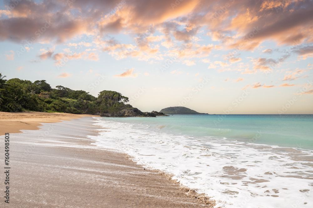 Deserted wide sandy beach with turquoise blue sea. Tropical plants of a bay at sunset in the Caribbean. Plage de Cluny, Basse Terre, Guadeloupe, French Antilles,