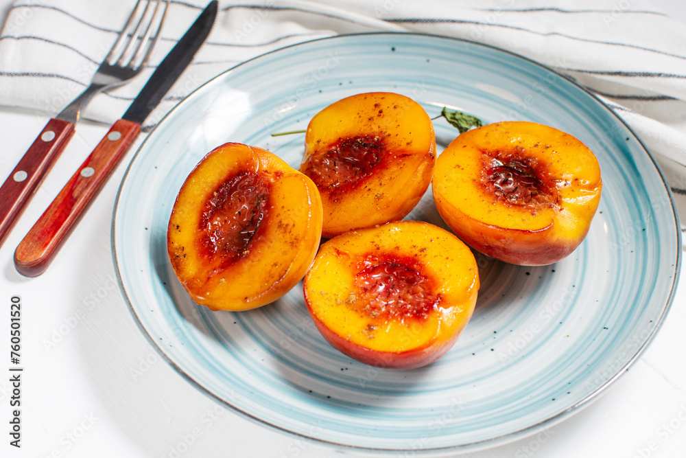 Baked peaches with honey and cinnamon in a ceramic plate. summer dessert