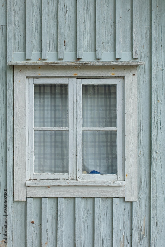 Closeup of white framed window on a green painted wooden wall.
