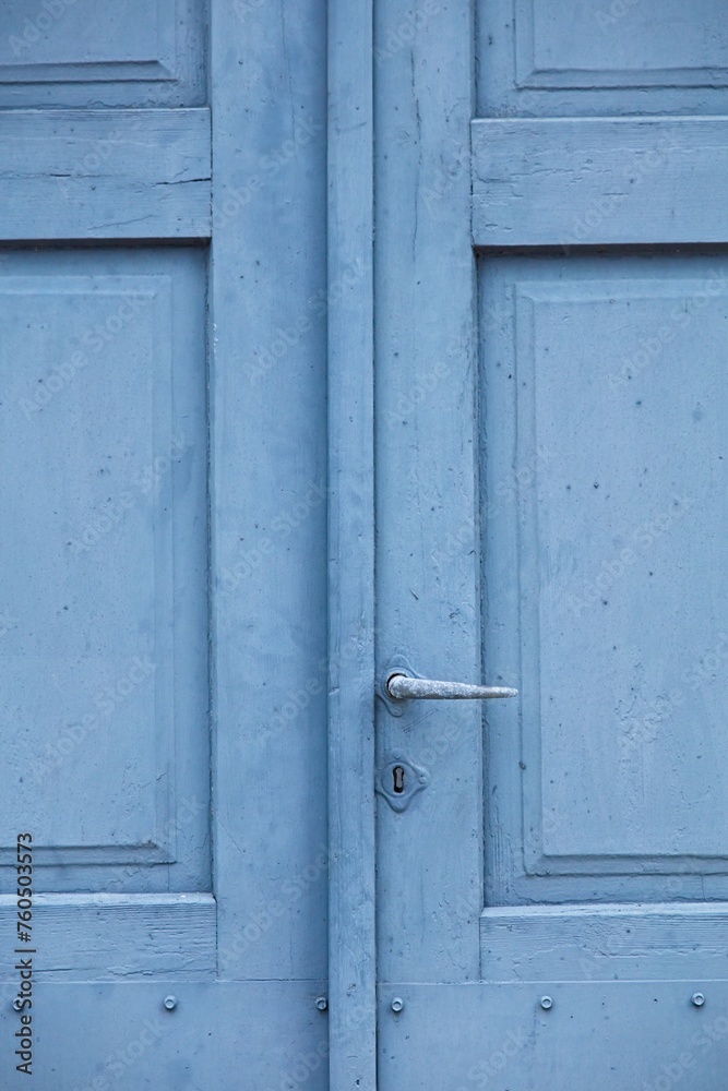 Closeup of weathered old blue wood door with keyhole and handle.