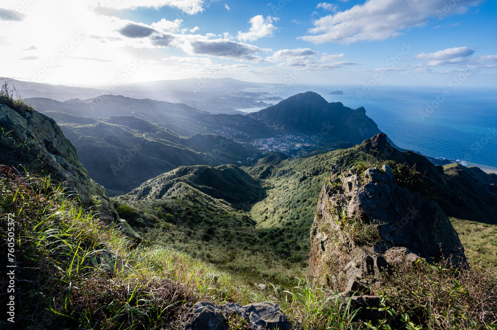 Fototapeta premium Overlook Keelung volcano groups from peak, grass covered mountains and ocean just nearby, sunlight shine on it, in Jiufen, Jinguashi, New Taipei City, Taiwan.