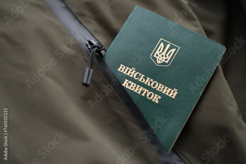 Military token or army ID ticket lies on green ukrainian military uniform indoors close up photo