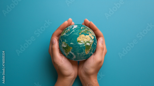 Concept of Environmental Care, Ecology, Sustainability and Climate Awareness: Hands Holding an Earth Globe on Pastel Blue Background. Happy Earth Day Concept with Copy Space