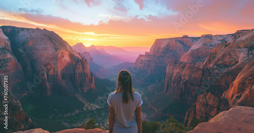 A woman standing on the edge of zion national park overlooking epic canyon landscape at sunrise photo