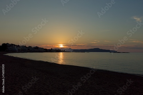 Sun going down late in the evening at Sunset beach in clear spring weather, Agioi Apostoloi, Crete, Greece.