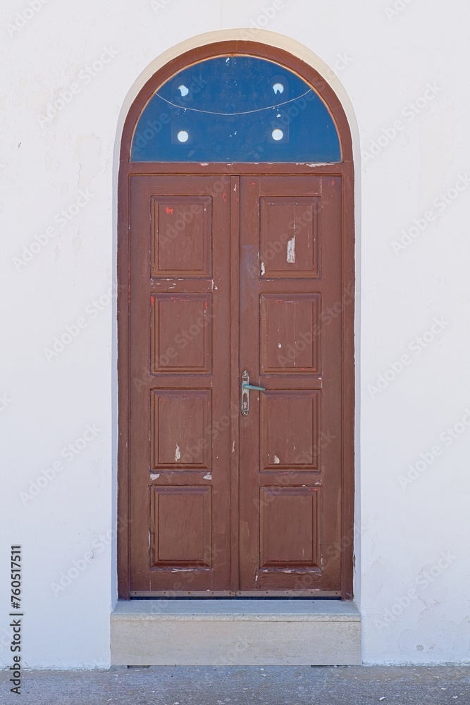 Old brown wooden door with glass arch on a white stone building. Old brown wooden door with glass arch on a white stone building.