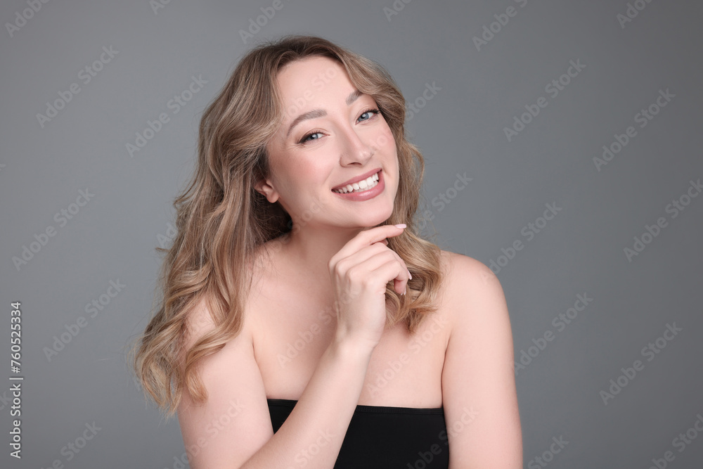 Portrait of smiling woman with curly hair on grey background Portrait of smiling woman with curly hair on grey background