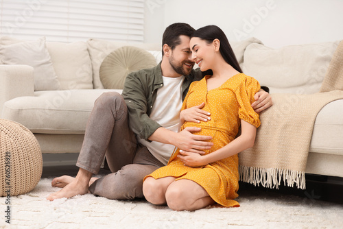 Happy pregnant woman spending time with her husband at home
