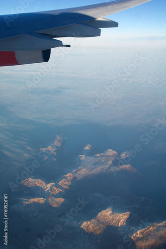 COPENHAGEN, DENMARK - 24 NOV 2018: Aeroplane window view with plane wing flying over the icebergs of Greenland at sunset with aerial perspective