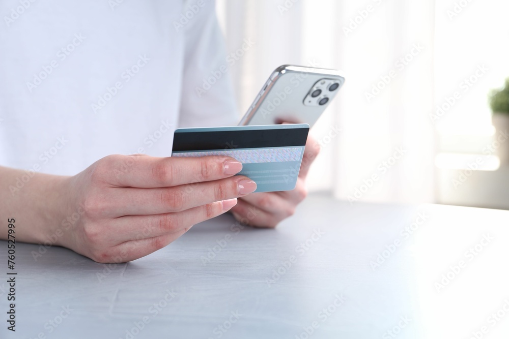 Online payment. Woman with smartphone and credit card at white table, closeup Online payment. Woman with smartphone and credit card at white table, closeup