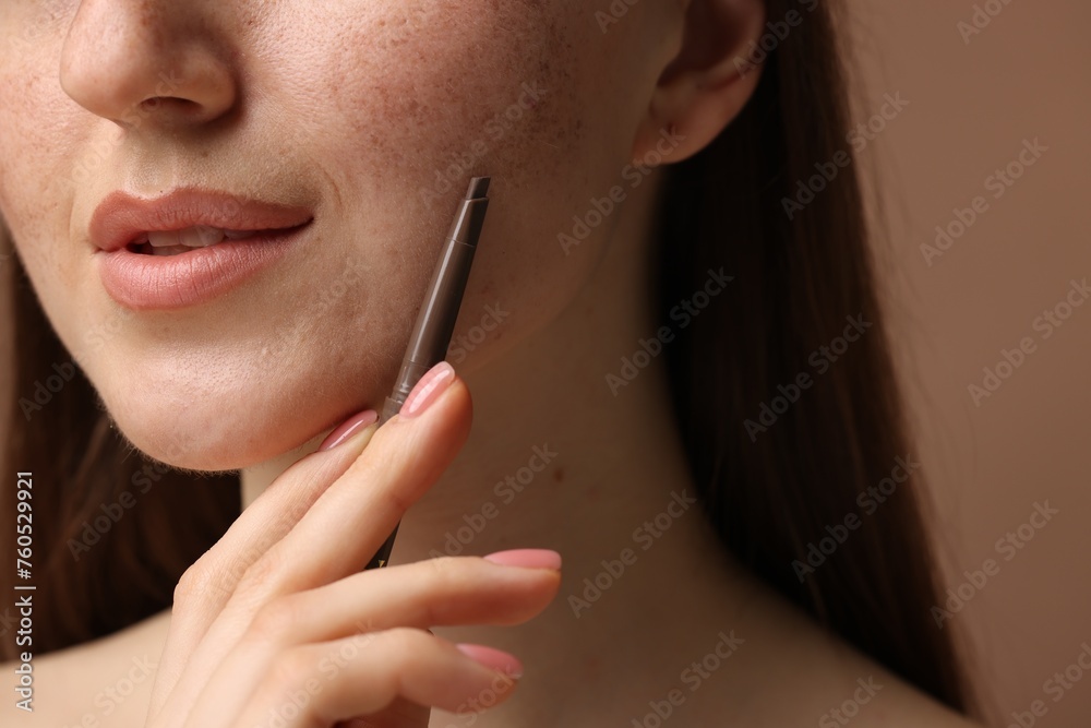 Beautiful woman with freckle pen on brown background, closeup