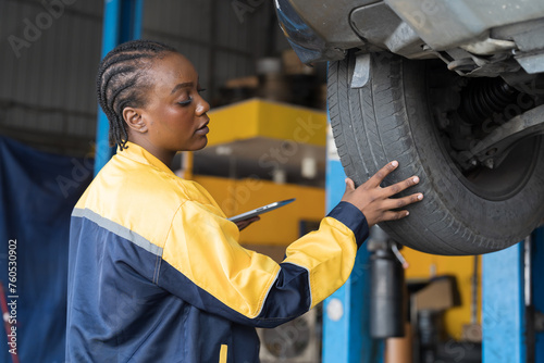 Female mechanic working at garage. Professional female mechanics checks, repair and maintenance tires car at auto car repair service. Car service and Maintenance concept photo