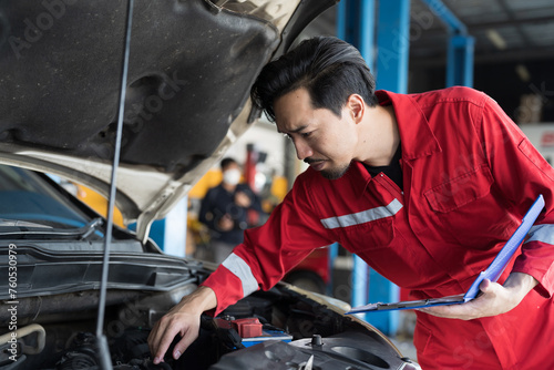 Male mechanic working at garage. Professional Asian male mechanics checks, repair and maintenance under hood of at auto car repair service. Car service and Maintenance concept