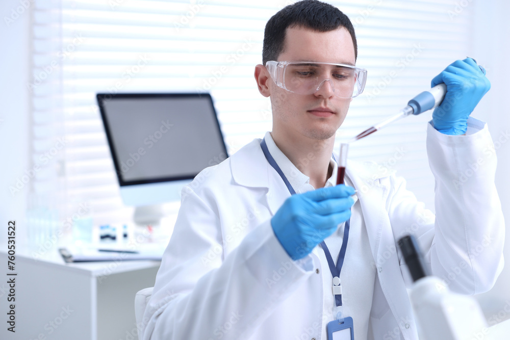 Scientist dripping sample into test tube in laboratory Scientist dripping sample into test tube in laboratory