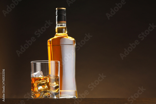 Whiskey with ice cubes in glass and bottle on table, space for text © New Africa