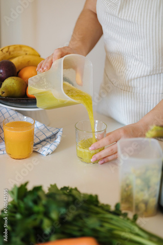 Middle selection of woman pouring fresh juice into glass. Homemade vegan beverage. Green drink