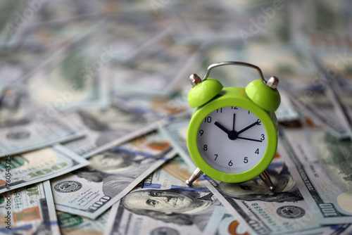 Alarm clock on hundred dollar bills banknotes. Background of time management, business and deadline concept