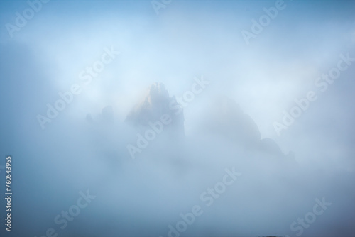 The sharp peaks of Tre Cime di Lavaredo are visible through the mist. Sexten Dolomiti, South Tyrol, Europe. photo